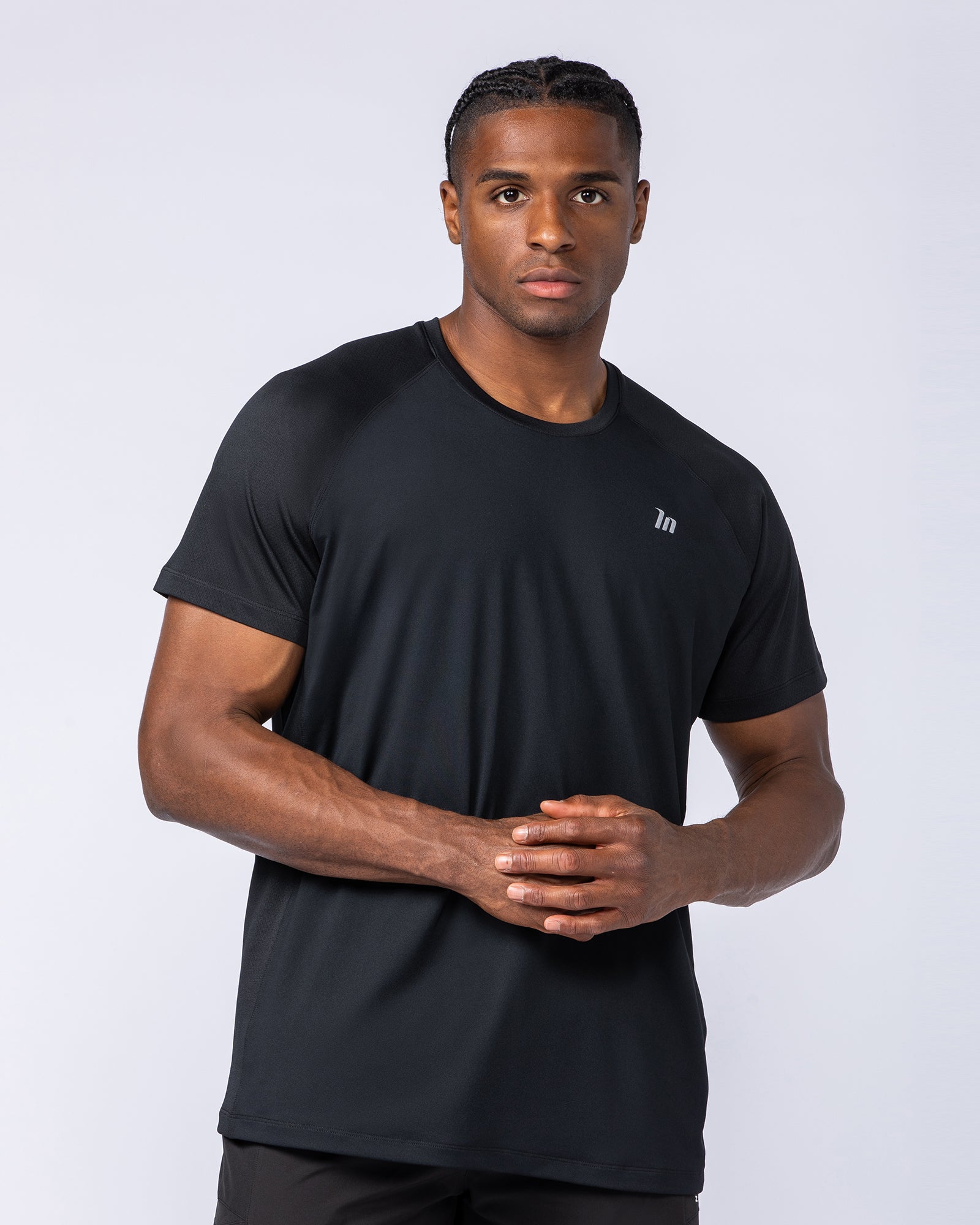Male model wearing the black Ventilation Tee, front view - Muscle Nation lightweight training tee with reflective chest logo